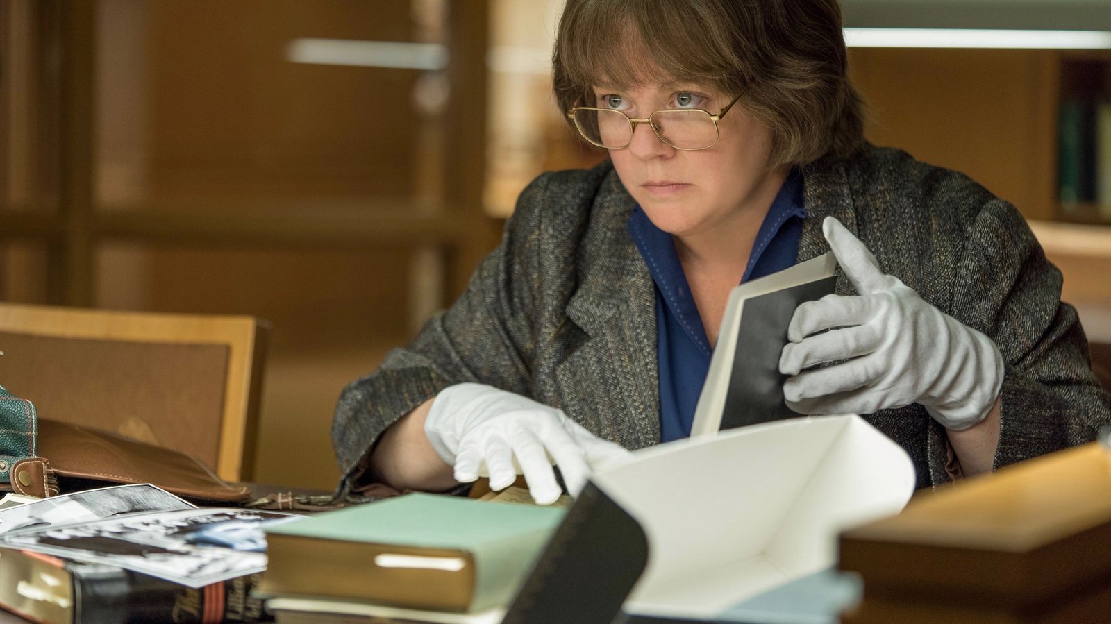 Lee Israel examining a photograph in white archive gloves