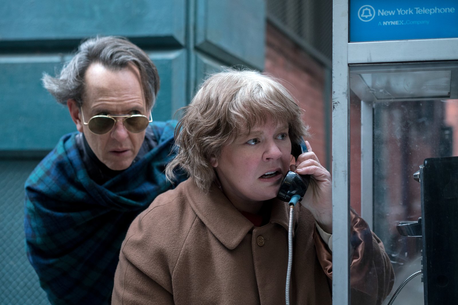 Lee Israel and Jack Hock at a New York pay phone, NYNEX signage above
