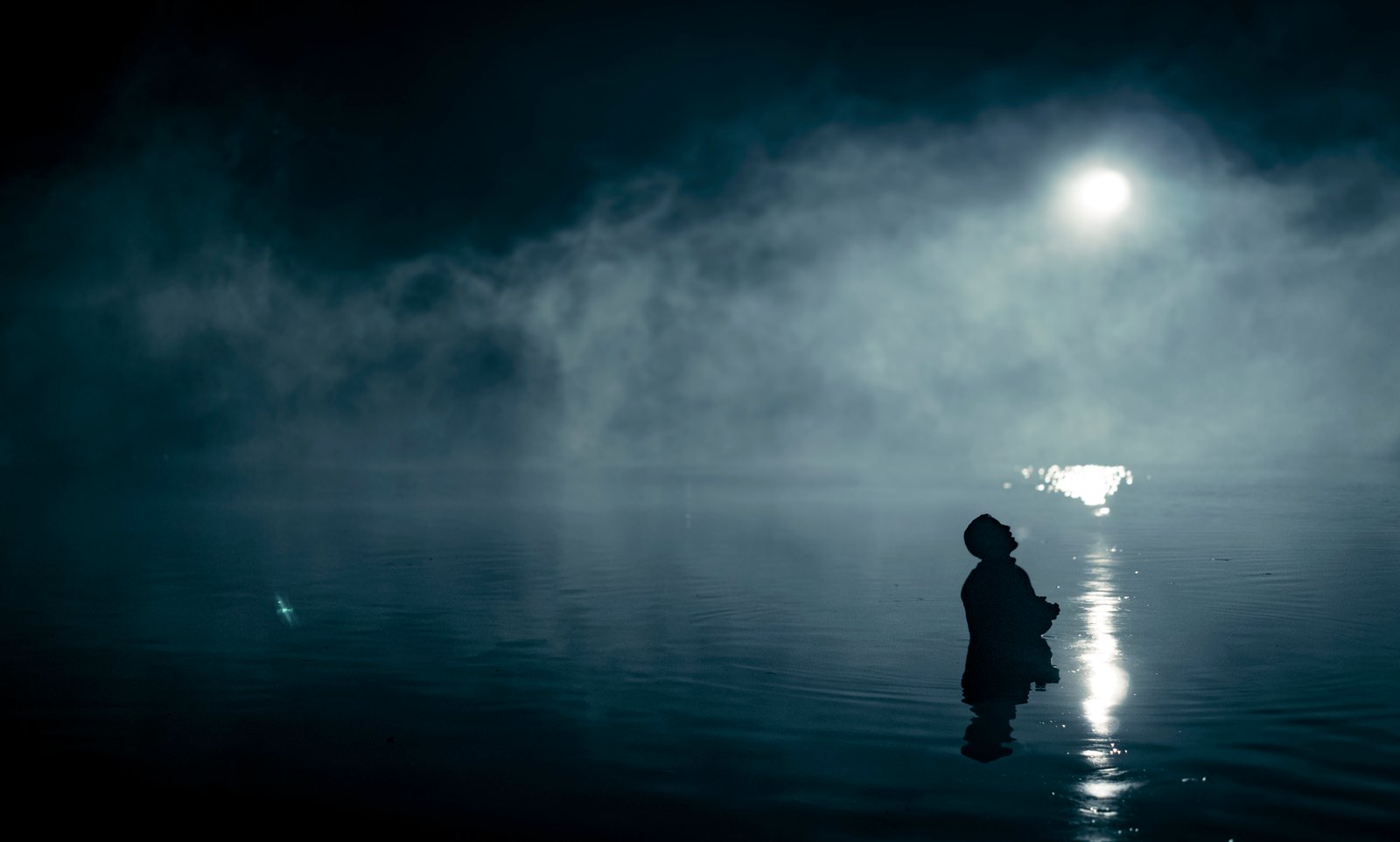 Silhouette waist-deep in a moonlit, fog-covered lake — Wormwood (Netflix)